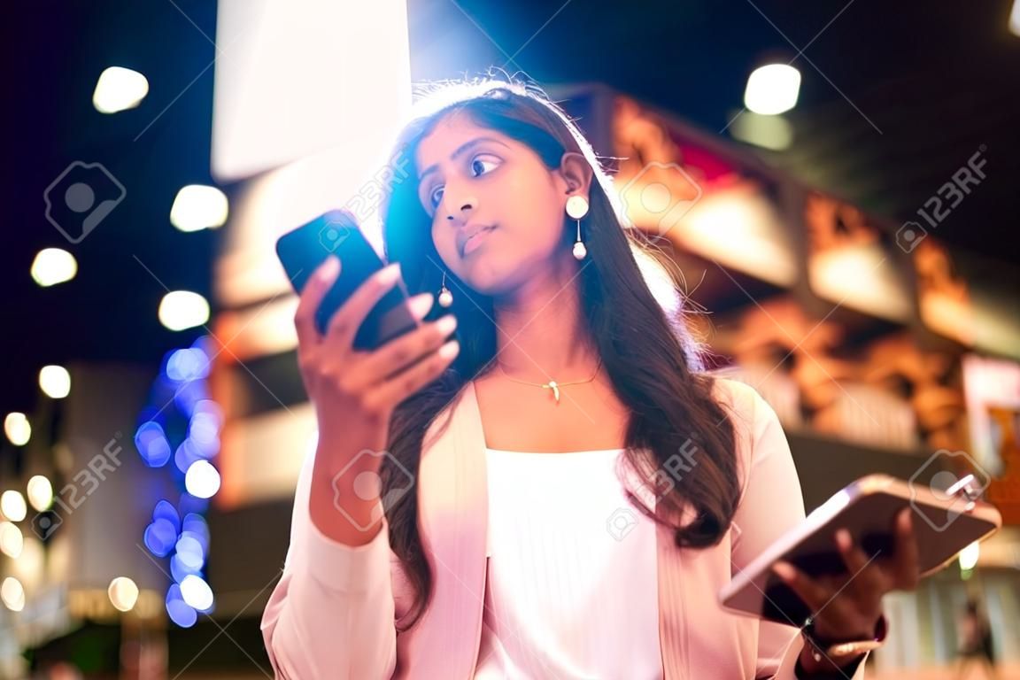 Jeune femme indienne avec téléphone portable dans une ville