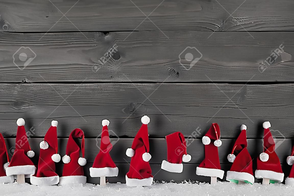 Humorously red, grey and white wooden christmas background with santa hats for a frame.