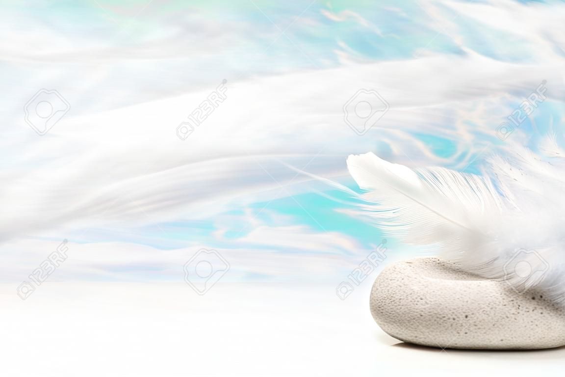 石の上に白い羽: お悔やみやスパのコンセプトの背景。グリーティング カードのためのアイデア。