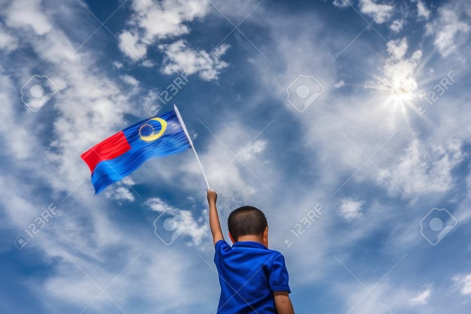 알 수없는 아이 흔들며 말레이시아 플래그. 독립 기념일 및 Merdeka 축하. 푸른 하늘과 복사본 공간입니다.