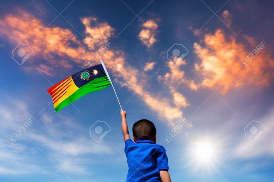 Bilinmeyen çocuk Malezya bayrağını salladı. Bağımsızlık günleri ve Merdeka Kutlaması. Mavi gökyüzü ve kopyalama alanı.