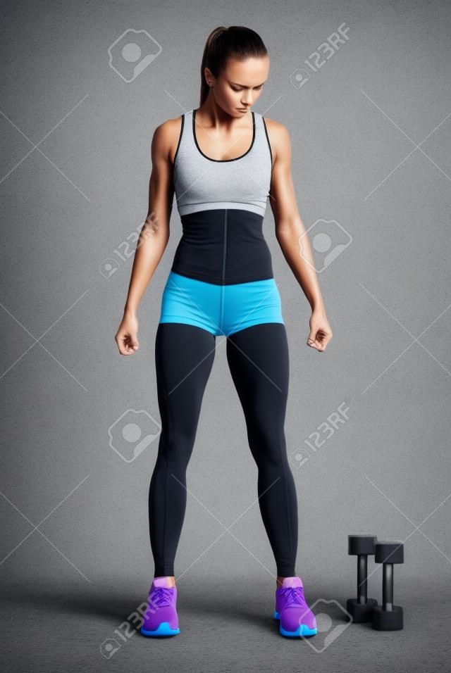 レッグウエア ダンベル運動を行う準備ができて女性アスリートに収まります。強い abs 表示されています。画像クリッピングパスと。