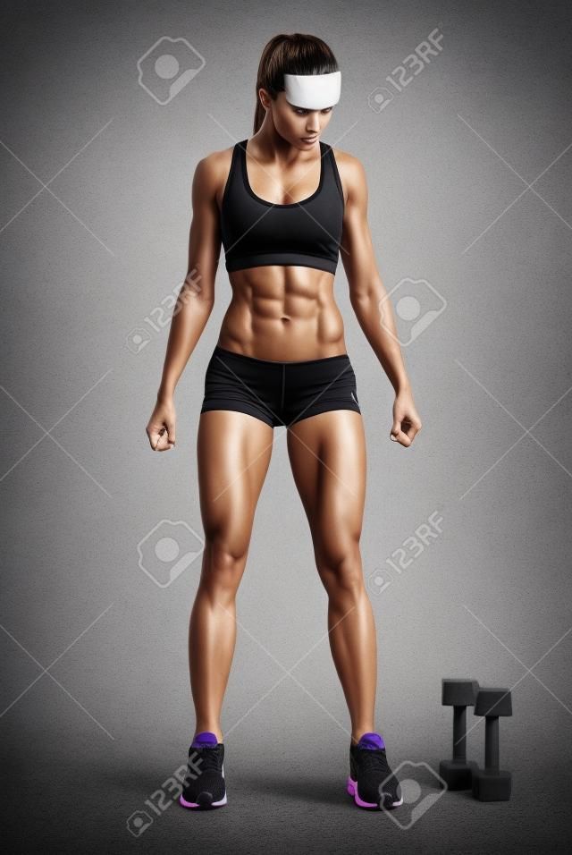 Fit női sportoló activewear készen áll, hogy csinál gyakorlatot súlyzókkal. Erős ABS mutatja. Kép vágógörbe.