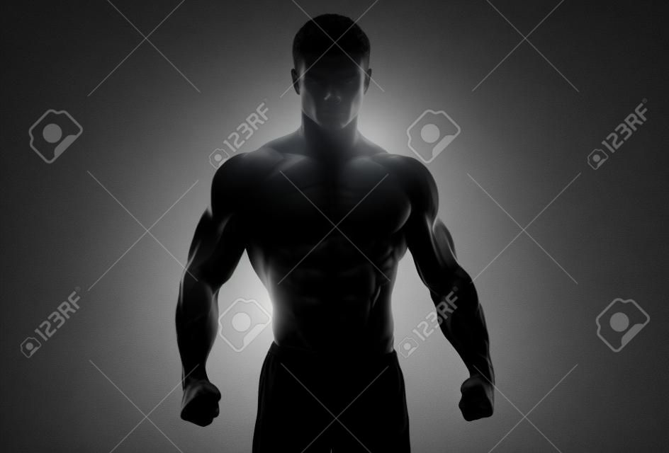 Dark silhouette of a strong man on white background. Confident young fitness man with strong hands and clenched fists. Clipping path inside