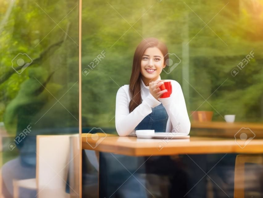 young woman sitting next to windows in cafe 