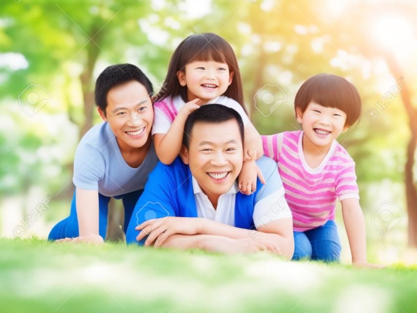 happy asian family with two children taking a family photo outdoors in a park.