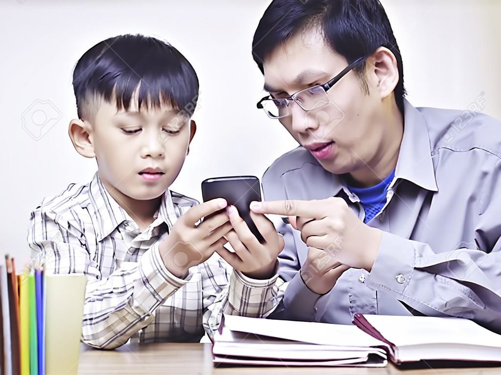 亞洲的父親和10歲的兒子與手機一起玩。
