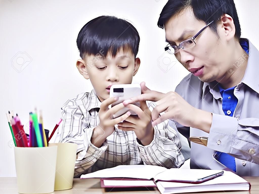 アジアの父と携帯電話を一緒に遊んで 10 歳の息子。