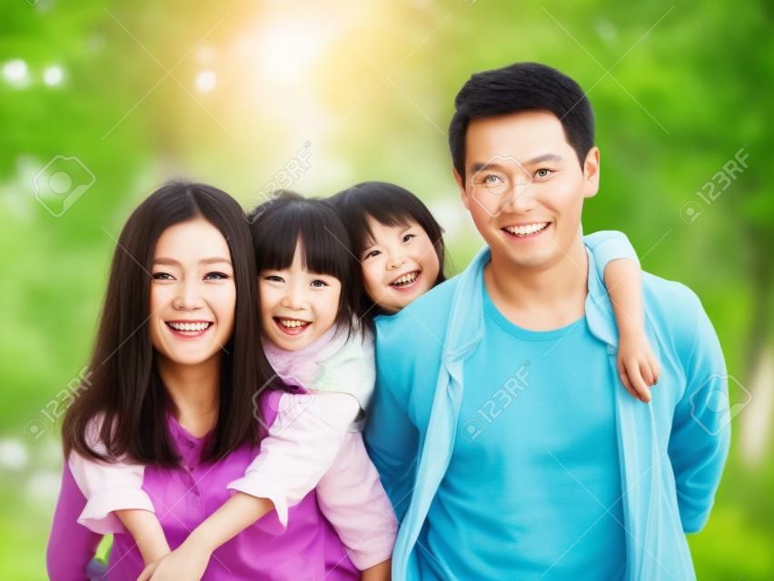 feliz família asiática com duas crianças dando um passeio no parque arborizado.