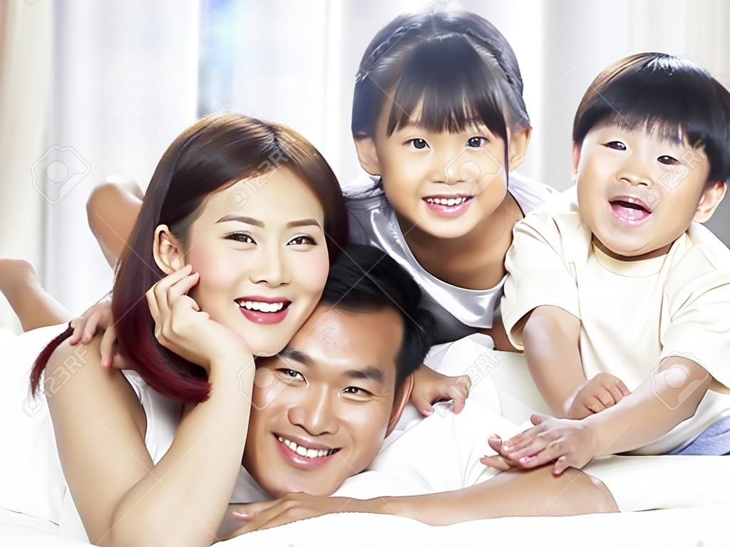 快乐的亚洲家庭，有两个孩子在家里开心地躺在床上