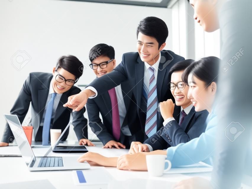 a team of asian business executives men and women working together in office using laptop computer.