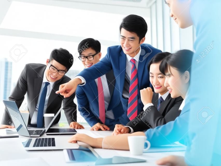 a team of asian business executives men and women working together in office using laptop computer.