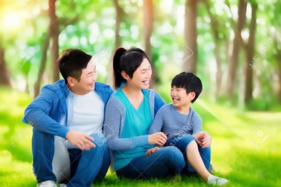 młodzi azjatyccy rodzice i syn bawią się na świeżym powietrzu w parku