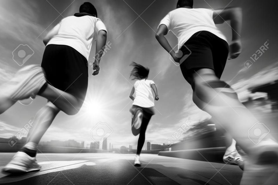 três jovens adultos asiáticos correndo jogging ao ar livre, vista traseira e baixa ângulo, preto e branco