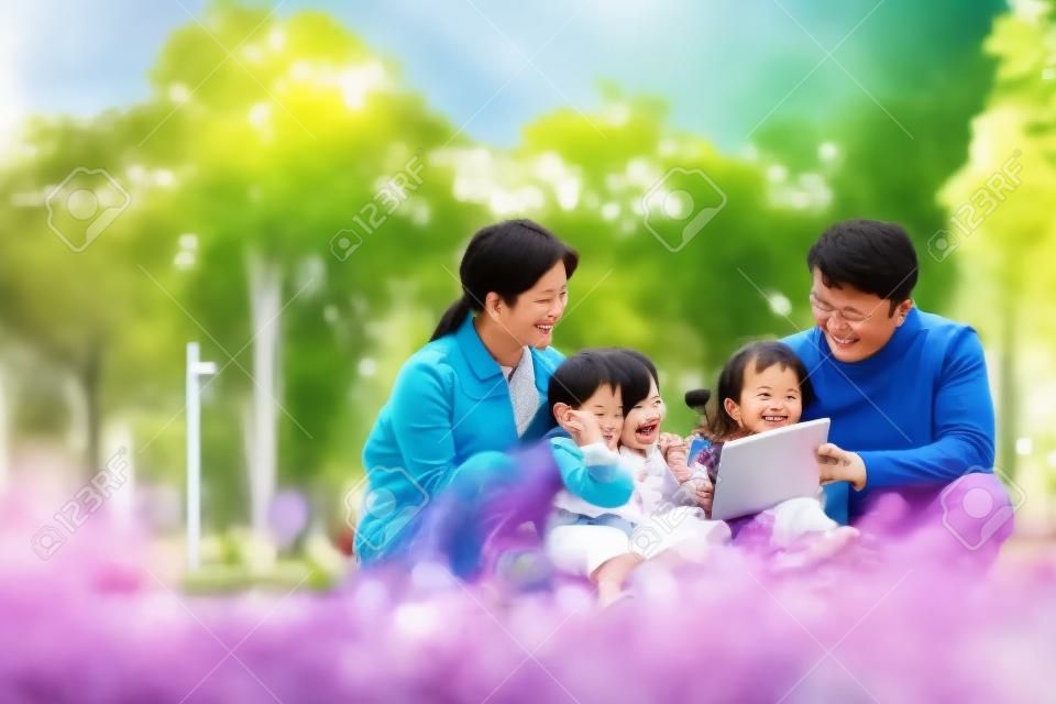 Família asiática com duas crianças relaxando ao ar livre no parque da cidade