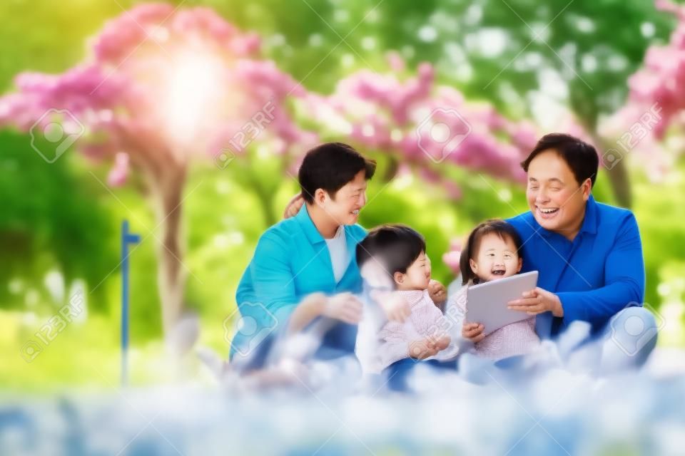 Família asiática com duas crianças relaxando ao ar livre no parque da cidade