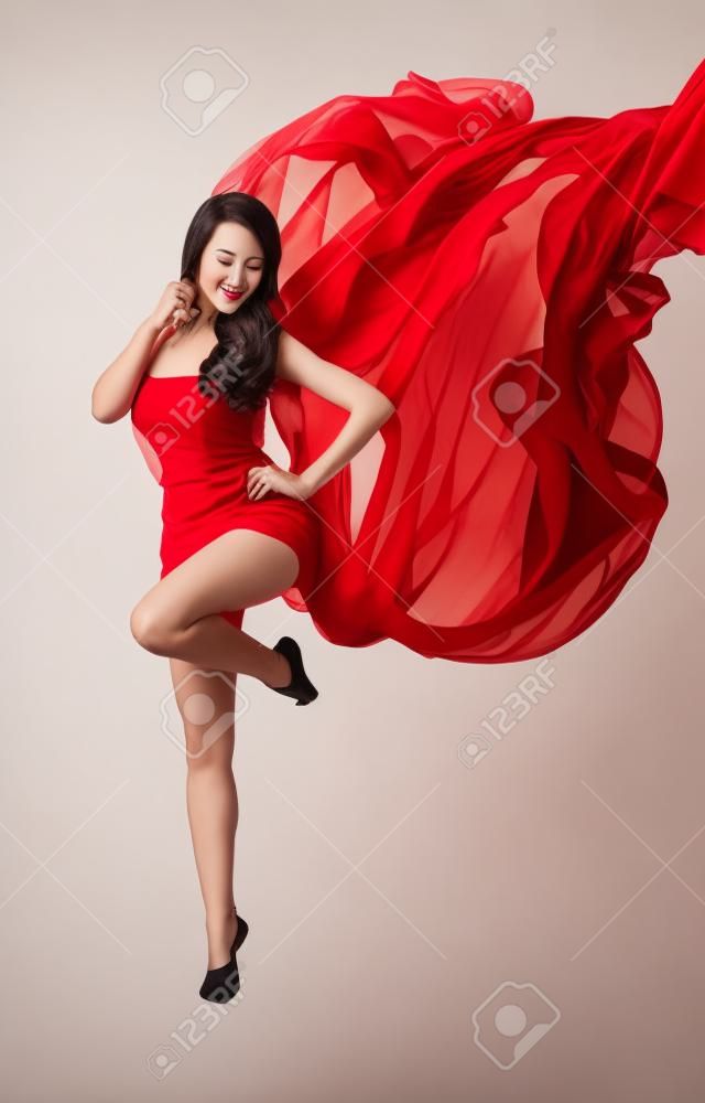 Mujer bailando en rojo vuelo agitando las alas vestido de gasa en un flujo de viento. Sobre fondo blanco