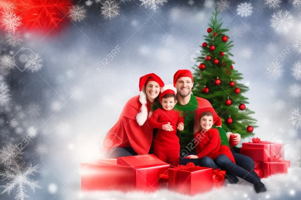 Navidad de la familia de cuatro personas y el árbol de abeto con cajas de regalo sobre fondo rojo