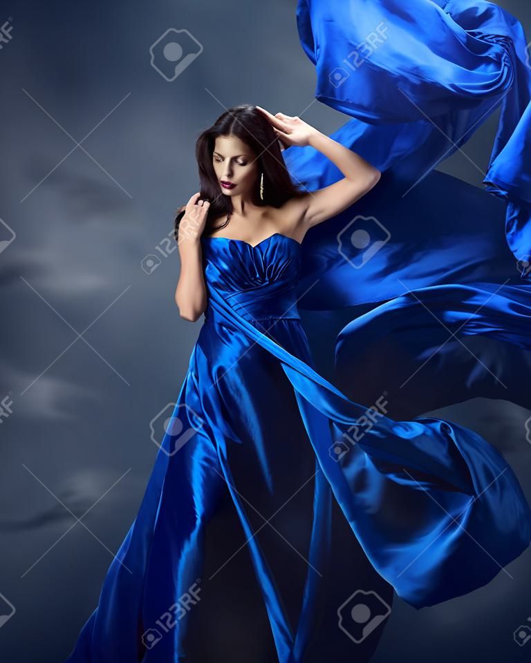 Mujer en vestido azul con la tela de seda volando