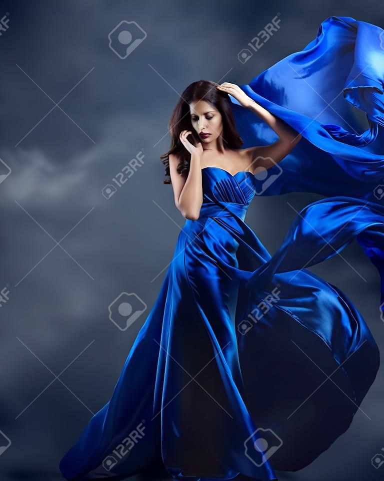 Mujer en vestido azul con la tela de seda volando