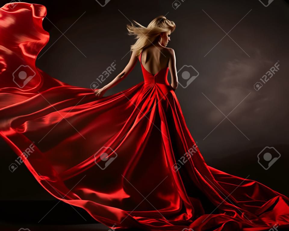 Woman in red waving dress with flying fabric. Back side view
