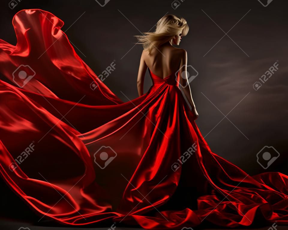 Woman in red waving dress with flying fabric. Back side view
