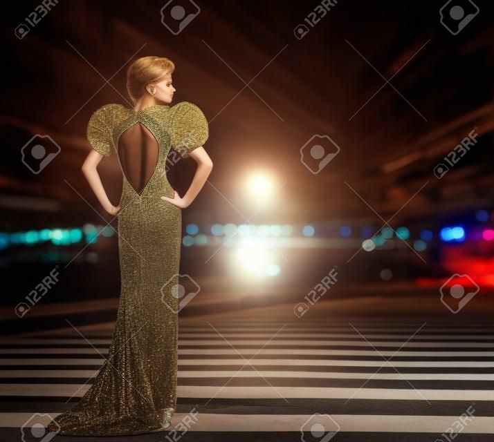 Vestido de noite de mulher Posing em luzes da noite da cidade, modelo de moda em vestido longo, vista traseira olhando para o lado, vida noturna urbana