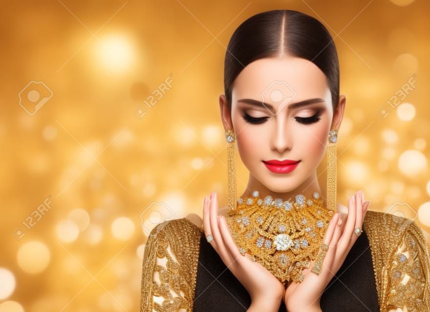 Fashion Model Holding Gouden sieraden in handen, vrouw gouden schoonheid, mooie meisje make-up en luxe sieraden