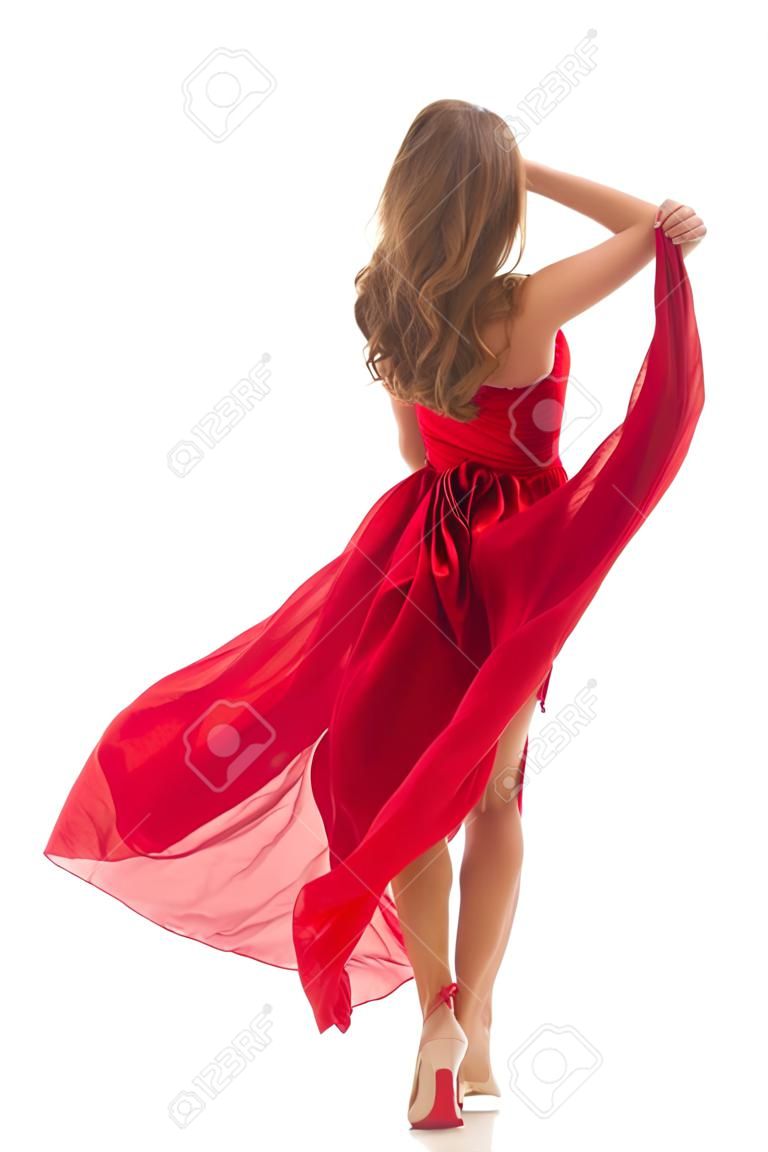 Kobieta z tyłu widok z tyłu chodząca w czerwonej sukience powiewająca na wietrze, dziewczyna w powiewających, machających ubraniach nad białymi