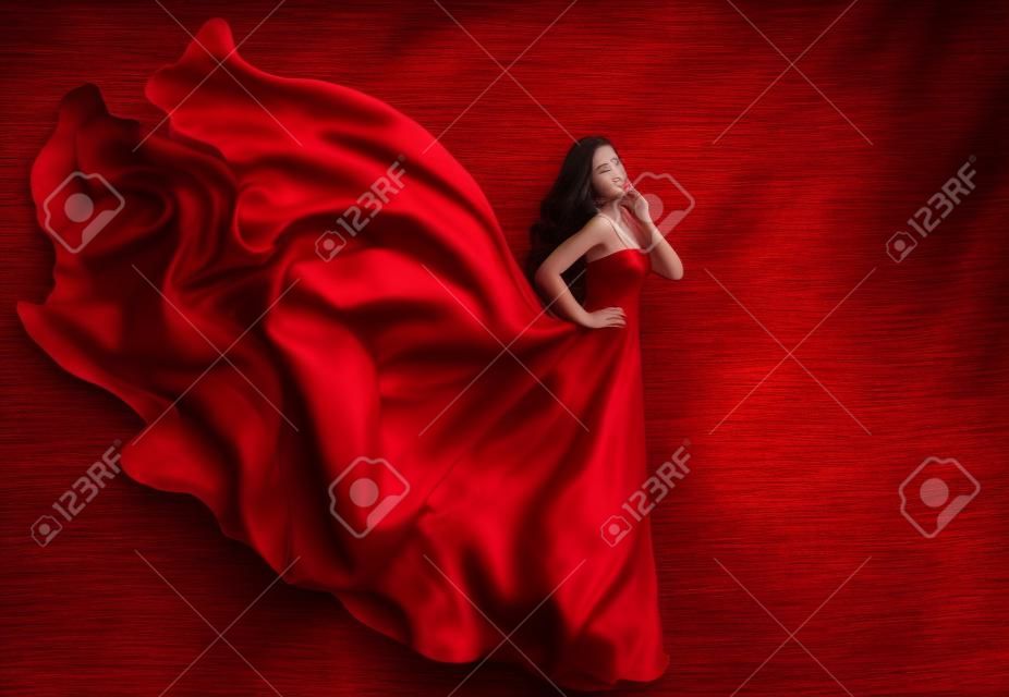 Vestido vermelho da mulher, modelo de moda em vestido de seda longo acenando no vento, menina de fantasia em tecido voador.