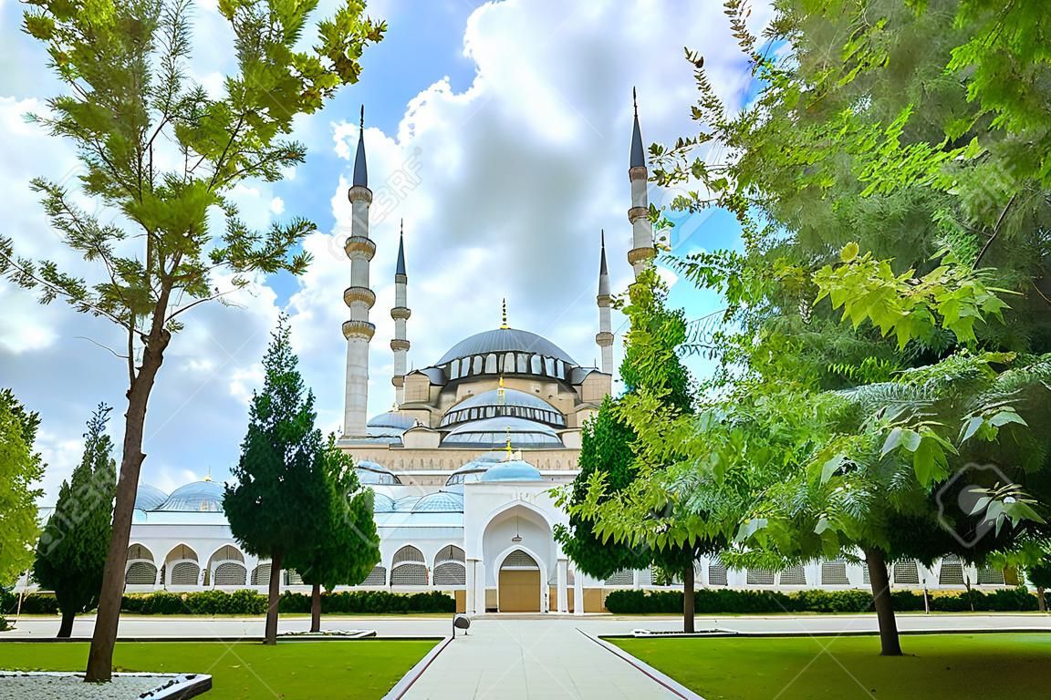Panoramisch uitzicht op de grootste Sabanci Central Moskee van Turkije in Adana tussen helder gebladerte van bomen en dramatische lucht