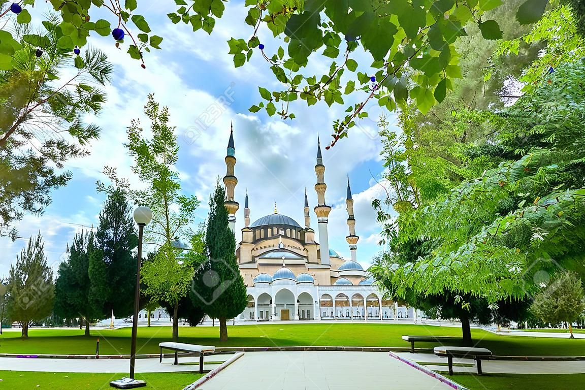 Panoramisch uitzicht op de grootste Sabanci Central Moskee van Turkije in Adana tussen helder gebladerte van bomen en dramatische lucht