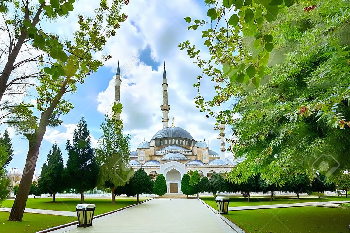 Panoramic view of Turkey's largest Sabanci Central Mosque in Adana among bright foliage of trees and dramatic sky