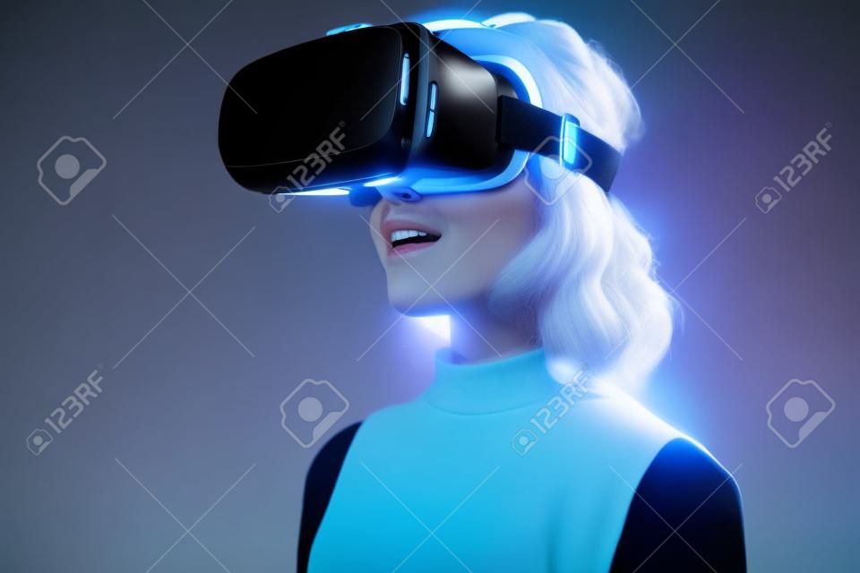 Woman wearing a futuristic looking virtual reality headset goggles.  The device is technology that lets video gamers experience VR or AR augmented reality
