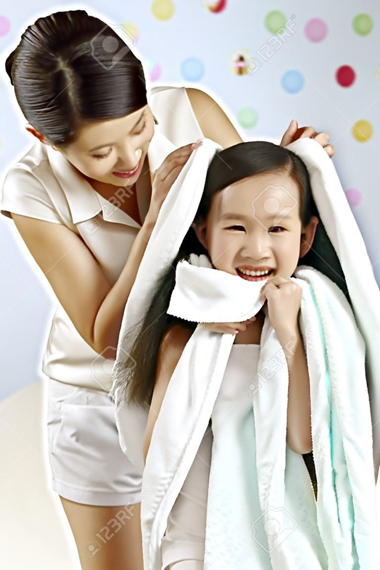 Woman drying girl's hair with towel