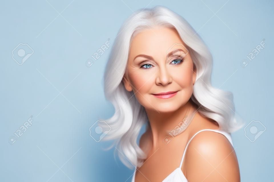 Ritratto di donna di mezza età che fa pubblicità al viso e alla cura del corpo su sfondo bianco.