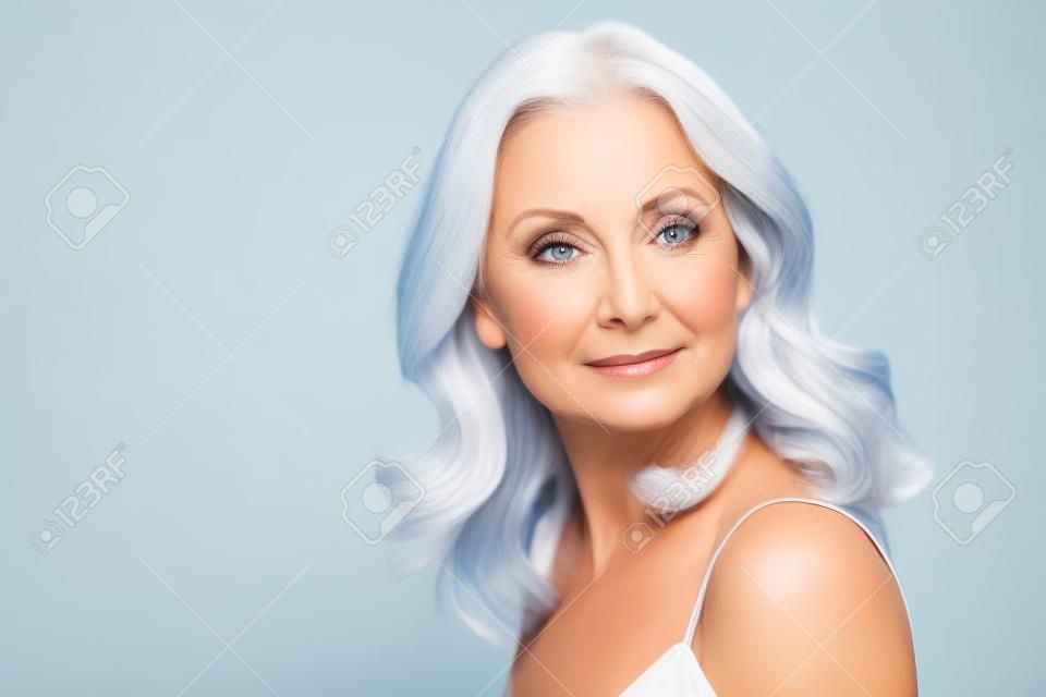 Ritratto di donna di mezza età che fa pubblicità al viso e alla cura del corpo su sfondo bianco.
