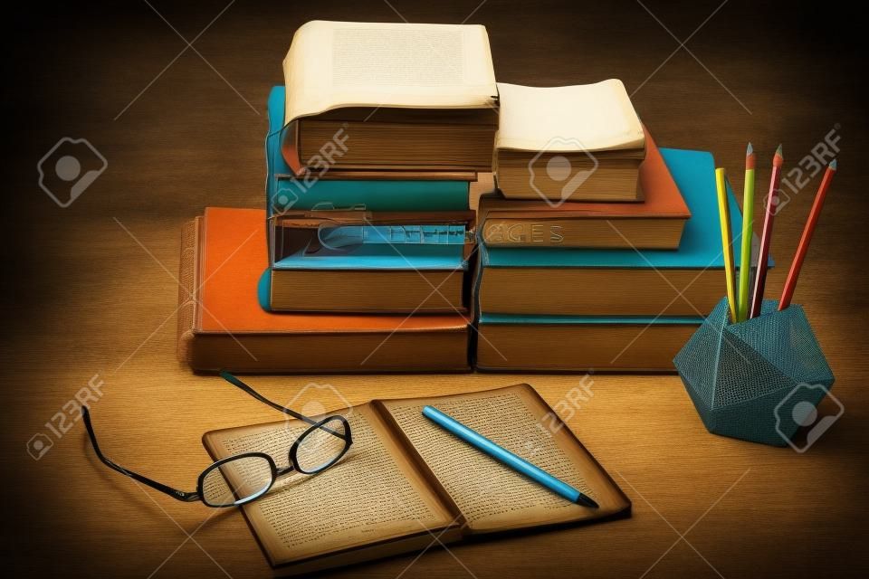 Pile de vieux livres, manuels, lunettes et crayons en arrière-plan de bureau pour le concept rétro de l'éducation