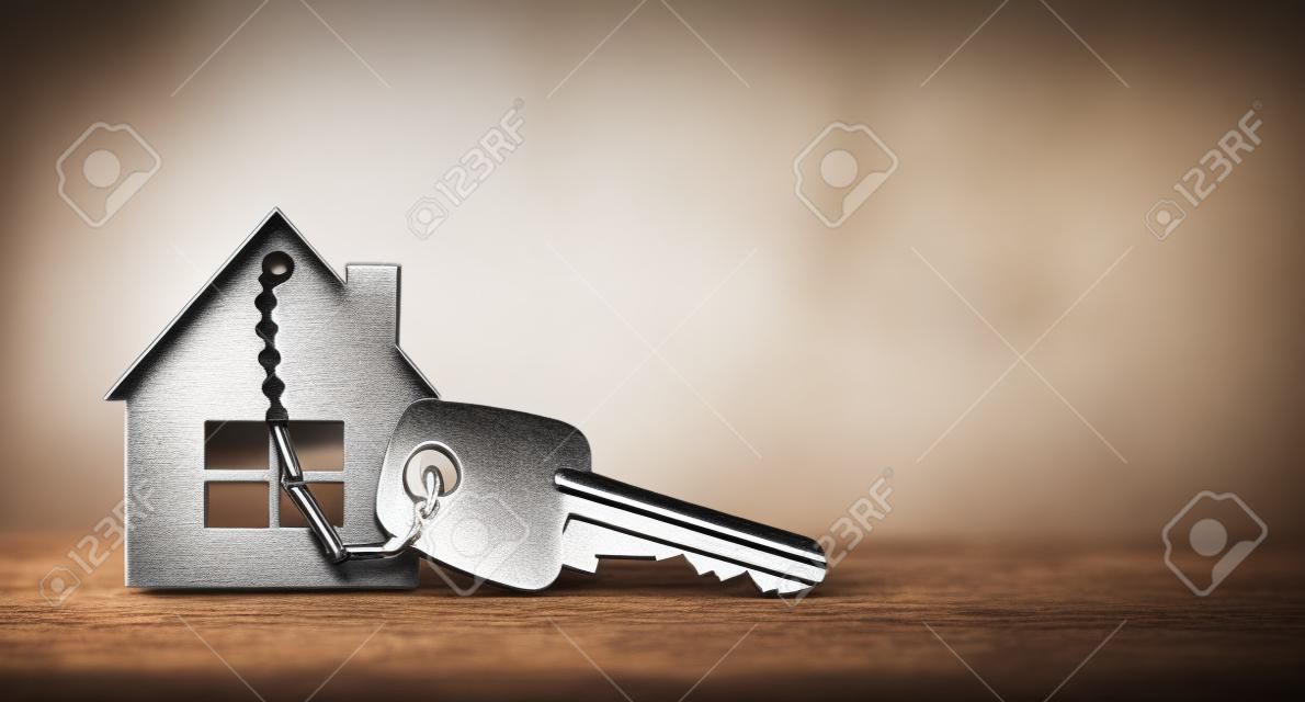 Símbolo de la casa con llaves de plata sobre madera. Concepto inmobiliario