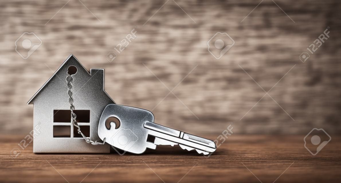 Símbolo de la casa con llaves de plata sobre madera. Concepto inmobiliario