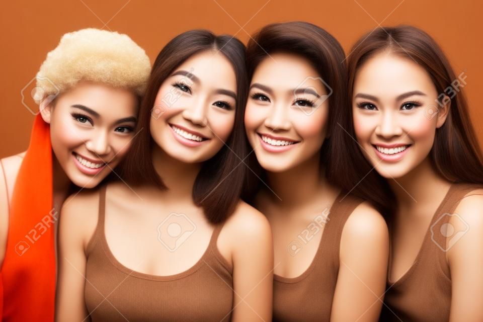 jeune jolie femme asiatique, caucasienne, afro posant gaie ensemble sur fond marron, concept de personnes de nationalité diversifiée de style de vie