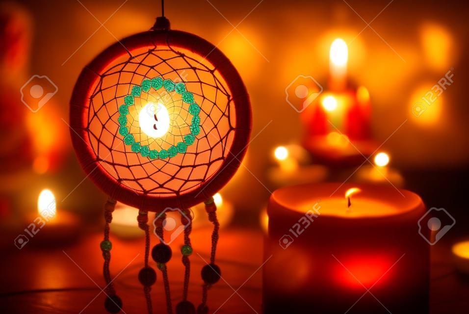 Vintage style image of dreamcatcher and candle light with blurred Buddha statue on the background.