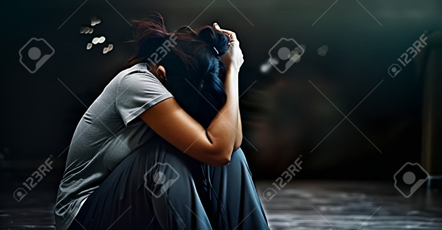 PTSD心理健康概念。创伤后应激障碍。沮丧的妇女单独在黑暗的屋子背景中坐地板。电影外观。