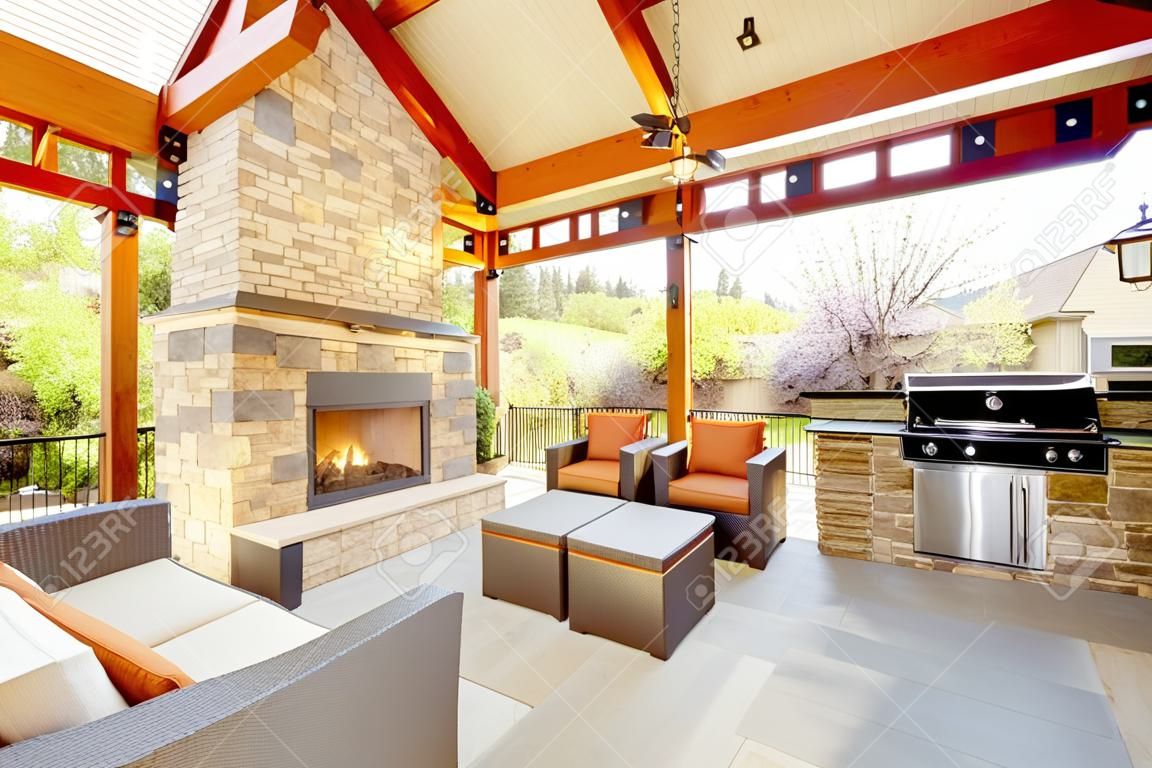 Exterior covered patio with fireplace and furniture. Wood ceiling with skylights.