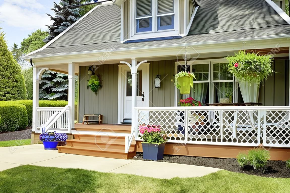 房子舒適的入口門廊。白色的欄杆融合與棕色的木地板和綠色的房子外觀