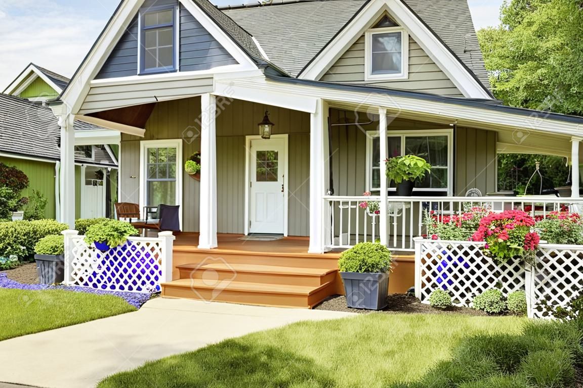 房子舒適的入口門廊。白色的欄杆融合與棕色的木地板和綠色的房子外觀