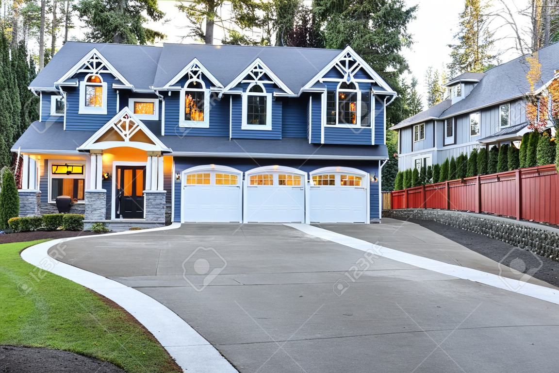 Luxurious home exterior with blue vinyl siding and white trim. Long concrete driveway lead to three attached garage spaces. Beautiful curb appeal. Northwest, USA