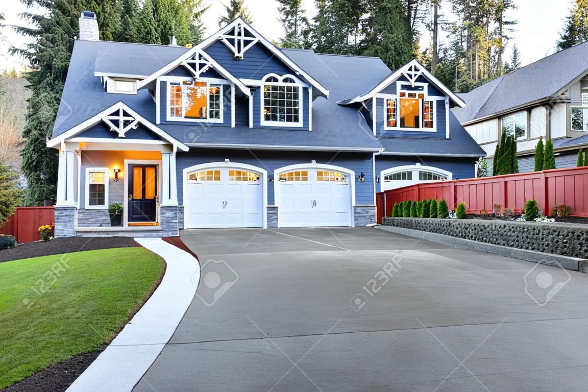 Luxurious home exterior with blue vinyl siding and white trim. Long concrete driveway lead to three attached garage spaces. Beautiful curb appeal. Northwest, USA