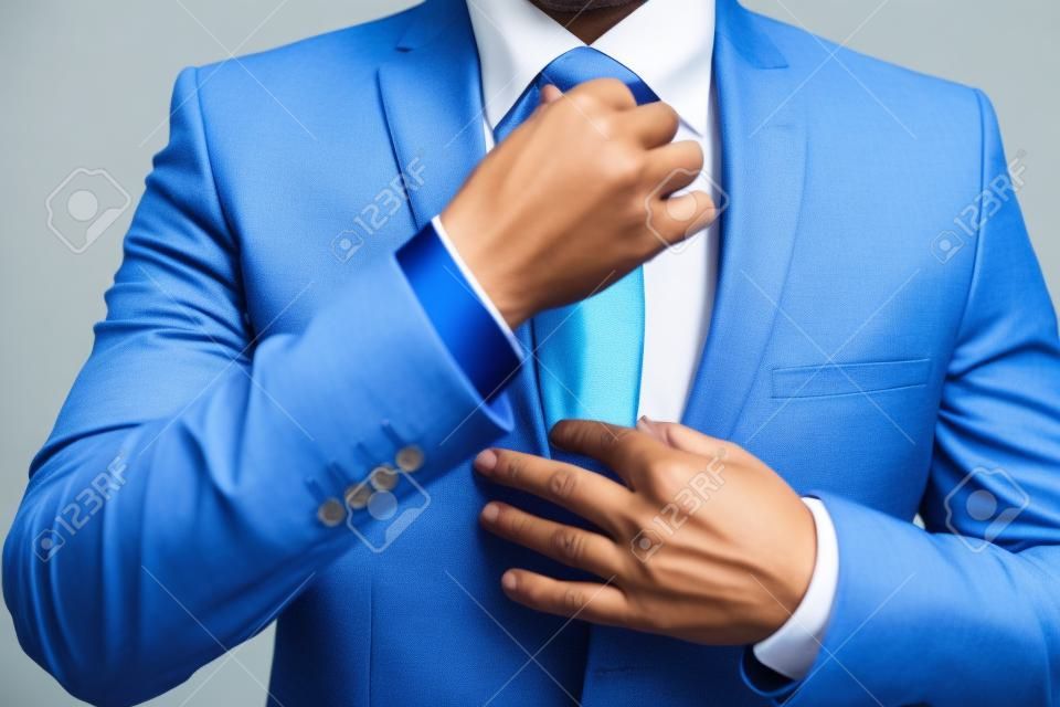 ネクタイを結ぶ青いスーツのビジネスマン