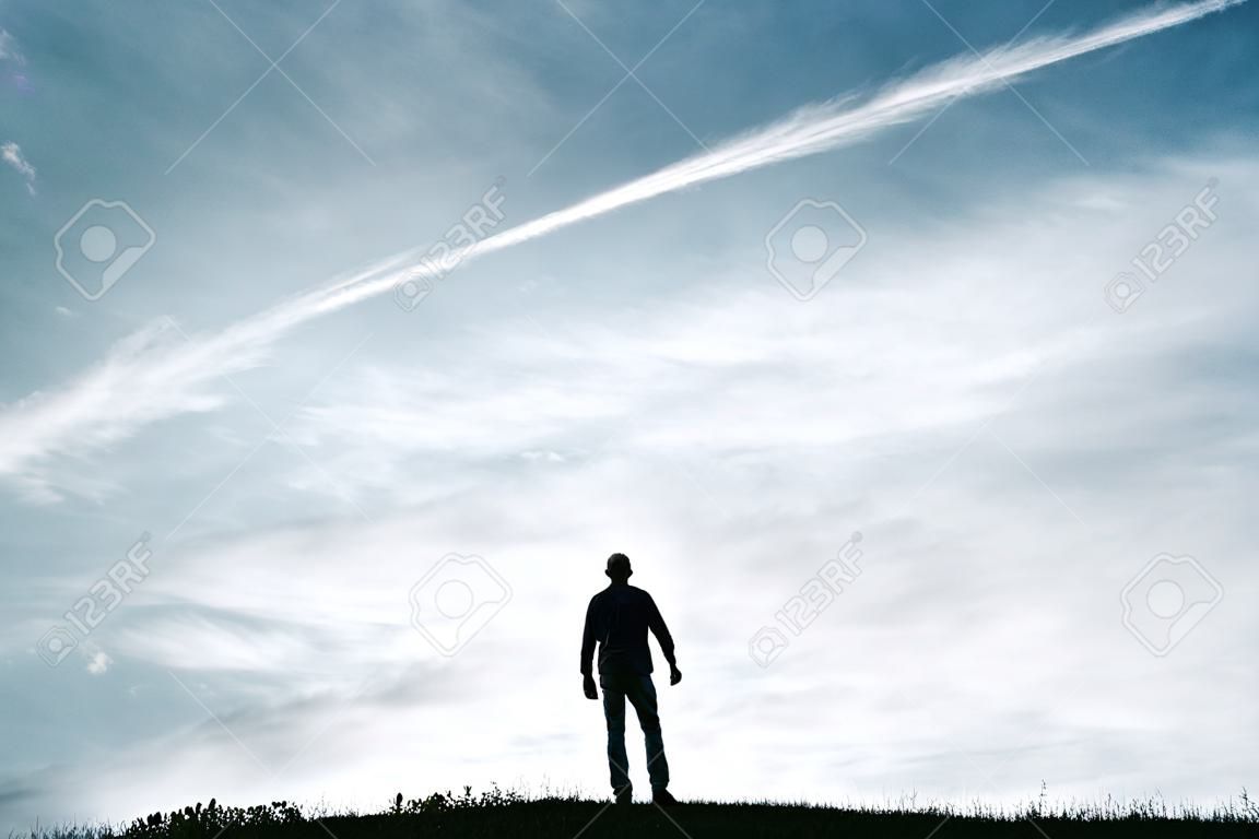 Mannsilhouette, die sich zwischen den Wolken im Berg frei fühlt